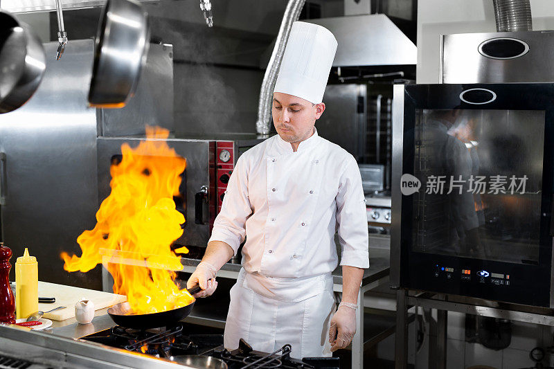 厨师在厨房炉灶上的煎锅中用火焰烹饪