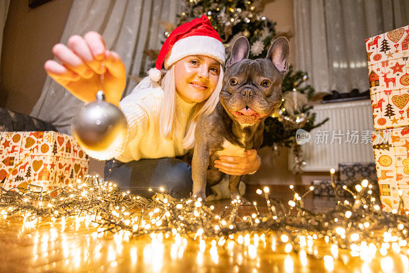 快乐快乐的年轻白人妇女与她的法国斗牛犬度过平安夜