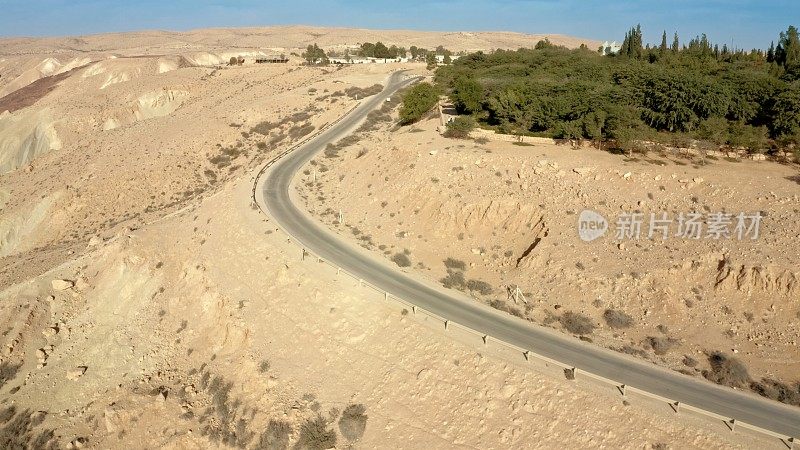 鸟瞰图的道路，通往一个绿色的公园与许多树木在山区沙漠