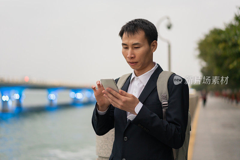 一名亚洲男子在海边使用智能手机