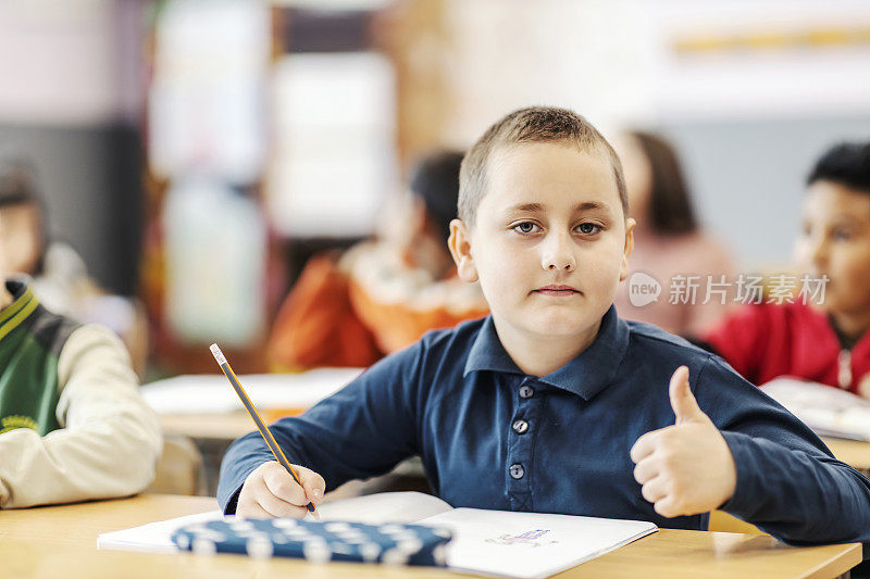 一个小学生对学校的良好教育竖起大拇指。