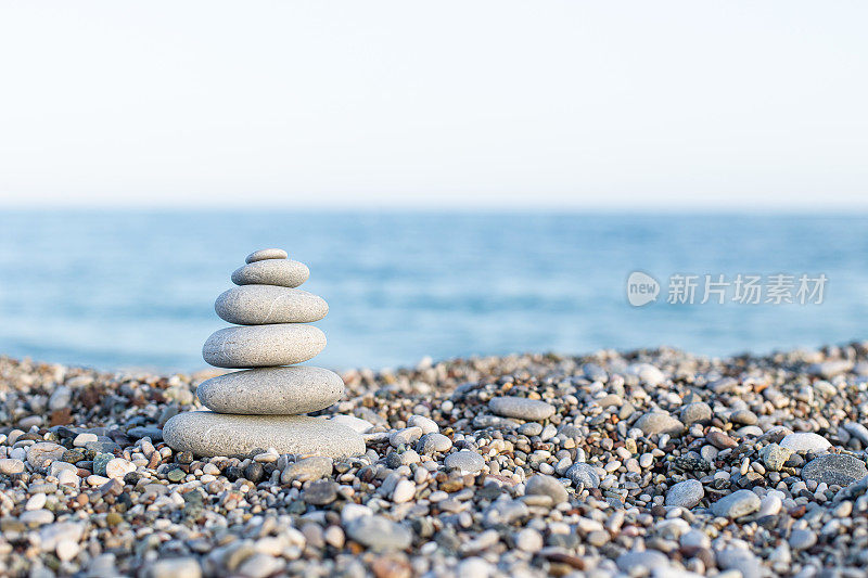 一堆堆石头堆在卵石滩上，在海浪中摇曳。冷静的概念