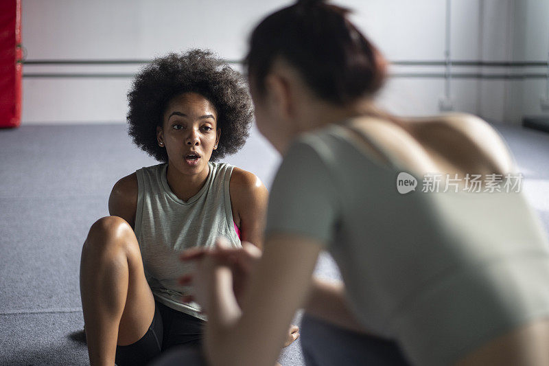 非裔美国妇女在健身房与亚洲朋友聊天