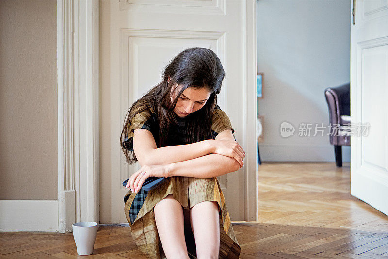 沮丧的年轻女子悲伤地站在家里