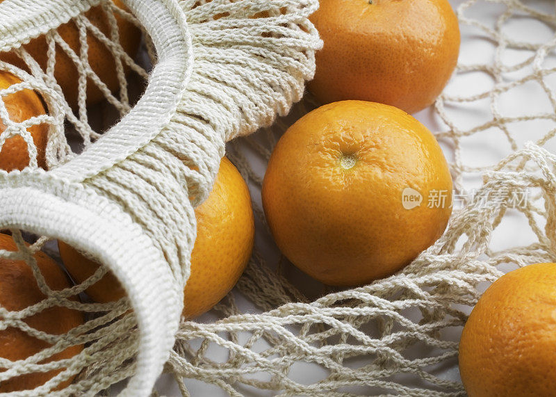 白色桌子上的布袋里装着橘子