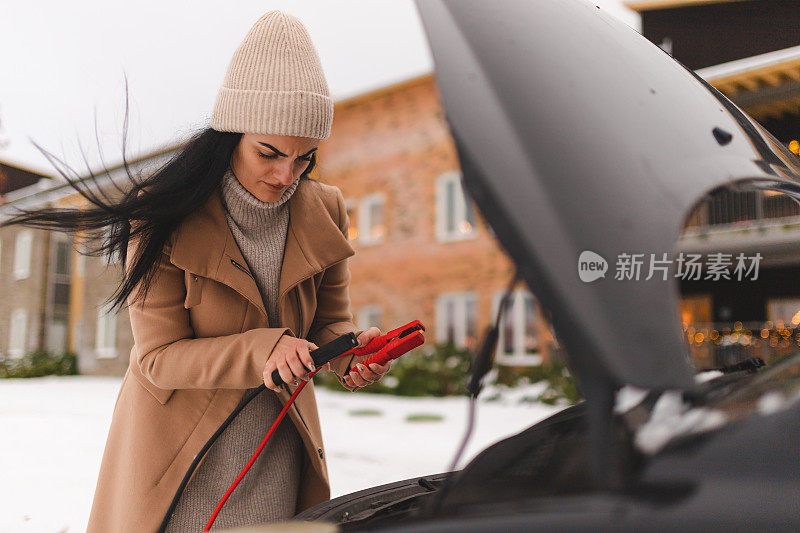 一名年轻女子试图弄清楚如何在冬天启动她的车