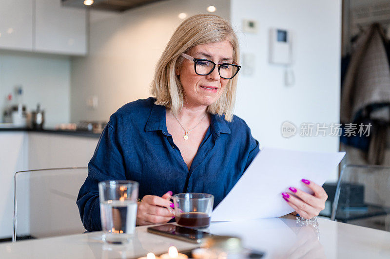 一位女士在家里一边喝咖啡一边看书