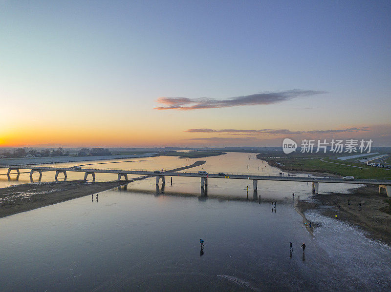 在美丽的冬日夕阳下，荷兰的湖面上滑冰