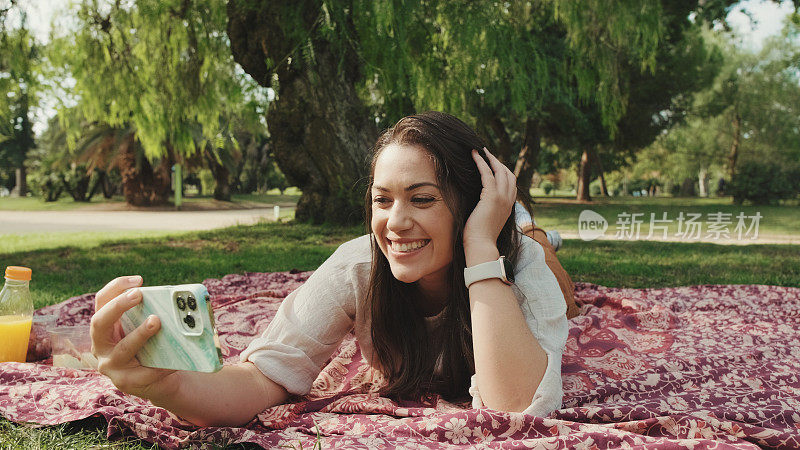 年轻女子在公园放松，用手机打视频电话