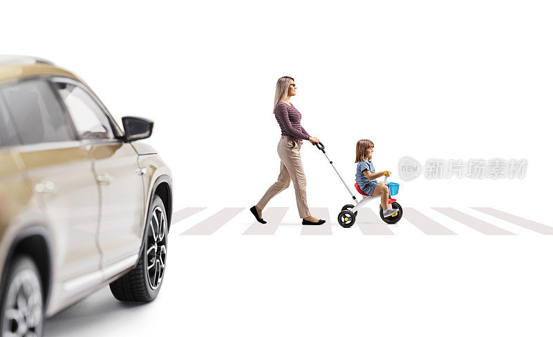 在白色背景的人行横道上，一辆汽车驶向一位推着三轮车的孩子的母亲