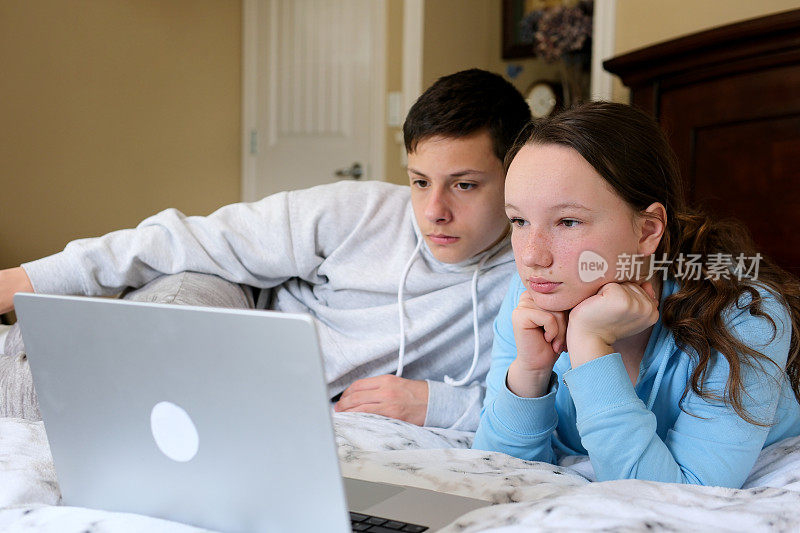 孩子们喜出望外，妹妹，弟弟笑着度过周末的空闲时间一起在家里的沙发床上吃爆米花。十几岁的孩子用笔记本电脑遥控器看卡通视频，玩得很开心。电影之夜