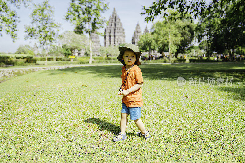 一个孩子走在草地上，背景是普兰巴南神庙