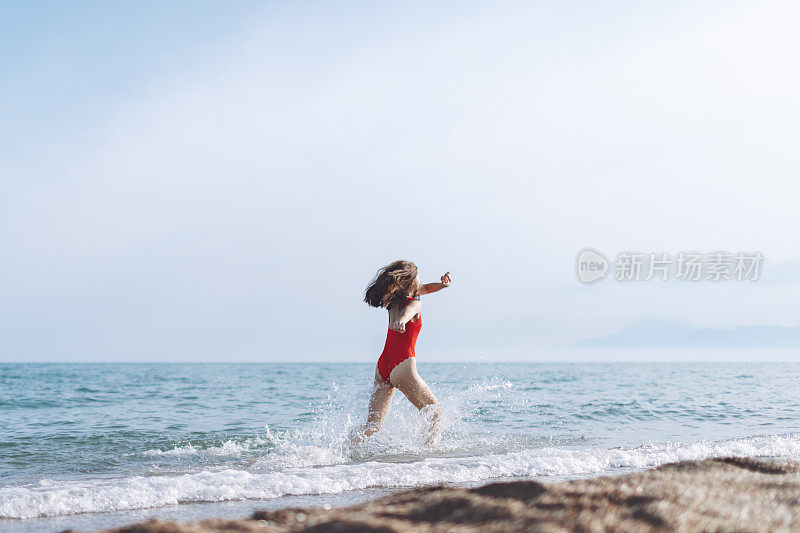 穿着红色泳装的年轻女子在海边玩耍