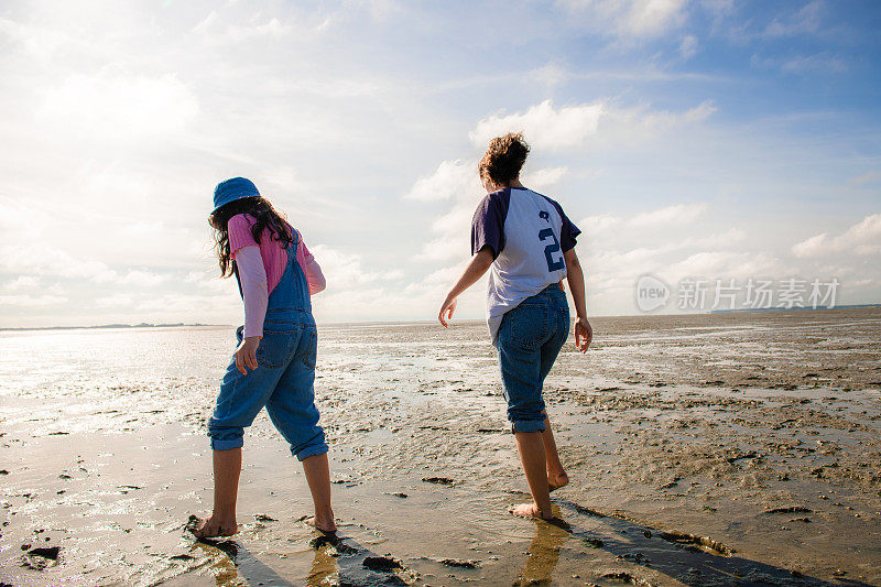 在法国的勒克罗托伊，两个女孩在退潮的海水中跟在家人身后