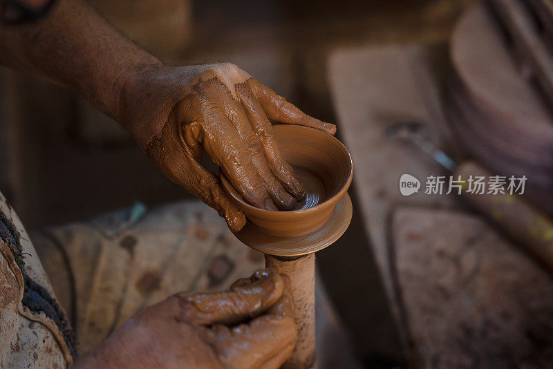 一位老人正在制作一个陶杯