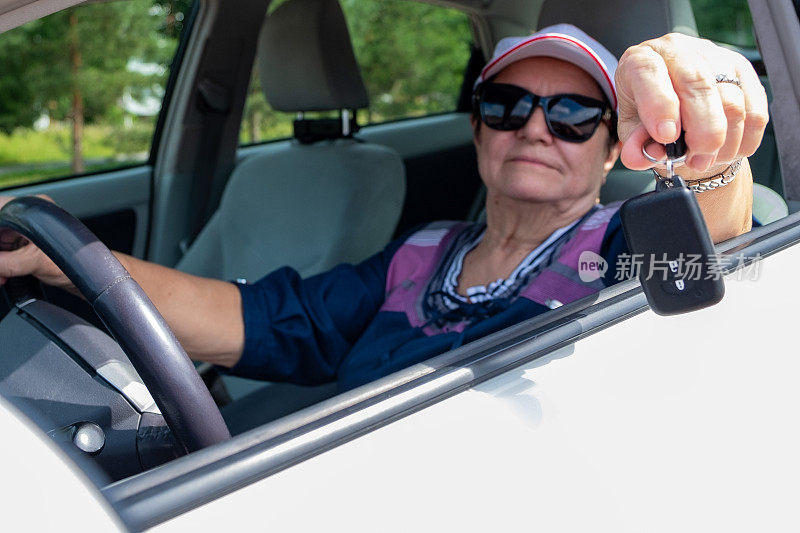 一位77岁的老妇人开着车，看着窗外，手里拿着车钥匙。