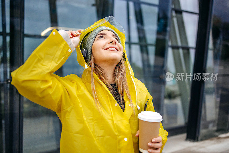 女人在下雨天穿着黄色雨衣去上班