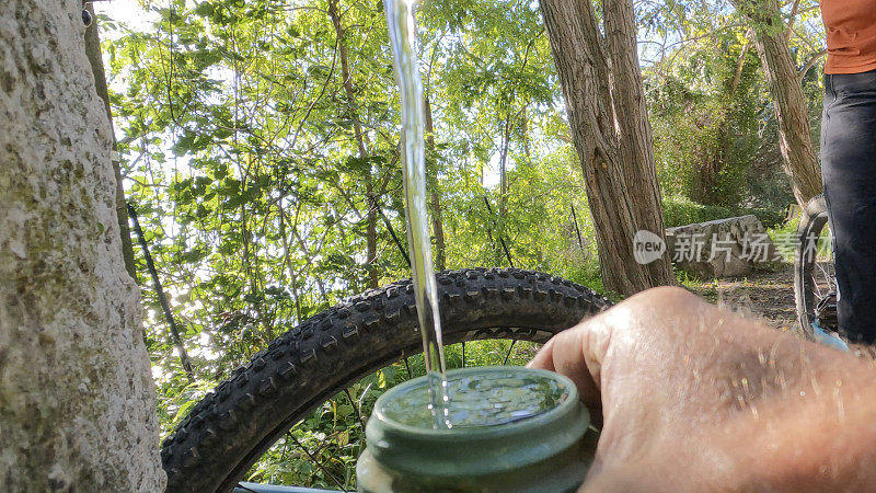 山地自行车手停下来给瓶子装水