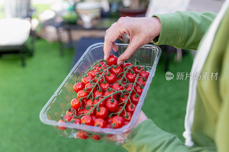 一个女人拿着一个装着西红柿的塑料容器