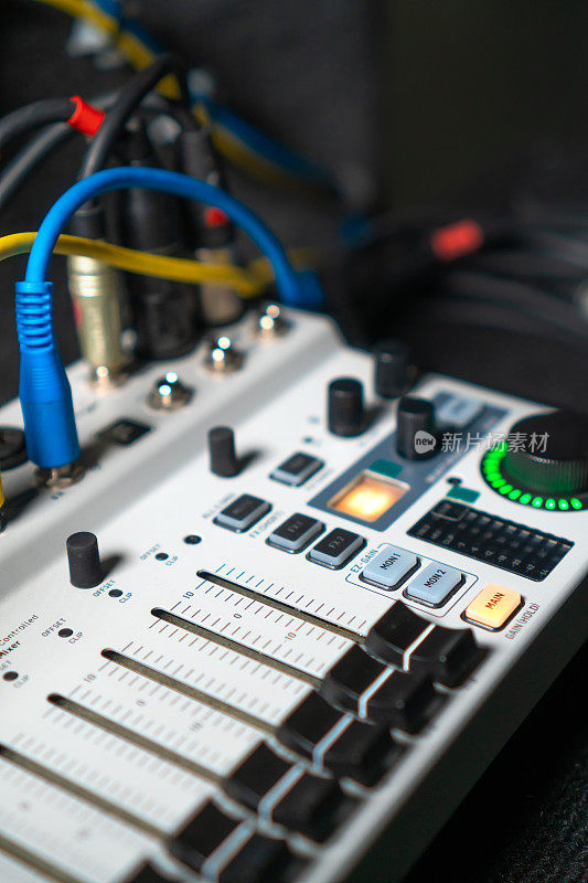 近距离图像的手调节混音旋钮的音量控制在现场演播室的表现。Mixer具有多个旋钮和按钮，用于精确的音频混合调整。垂直图