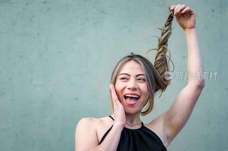 美丽的年轻女子的肖像玩她的头发在灰色背景