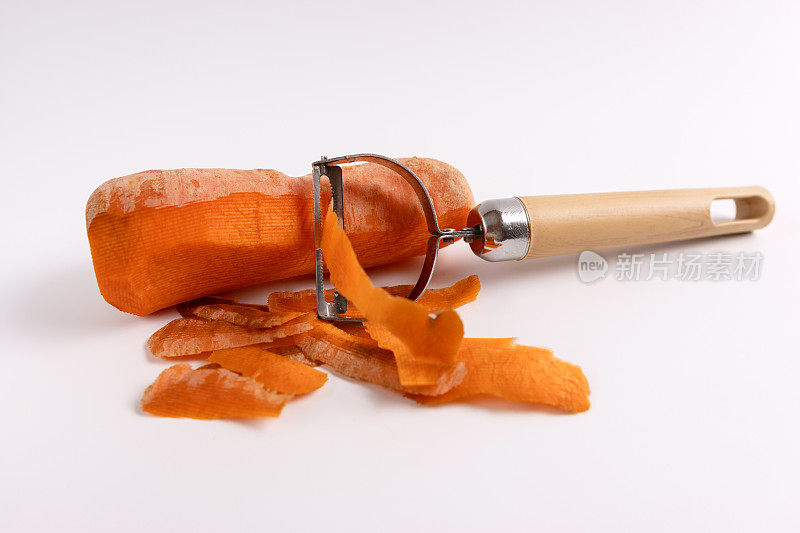 生胡萝卜和一把在白色背景上削皮的刀。