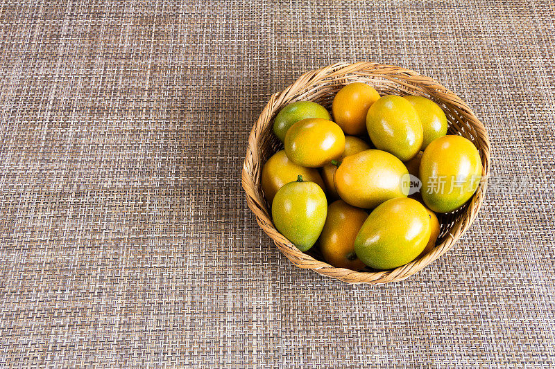美味成熟的黄色波卡多芒果果实在篮子里，有纹理的背景。加勒比热带水果。