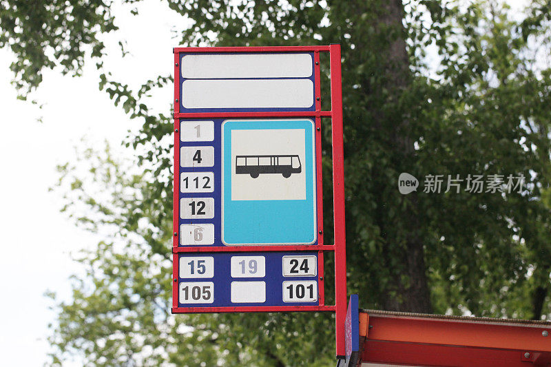 公交车站背景。公交票价上涨。公共交通费用。红色建筑孤立在树上。公交号码信息。
