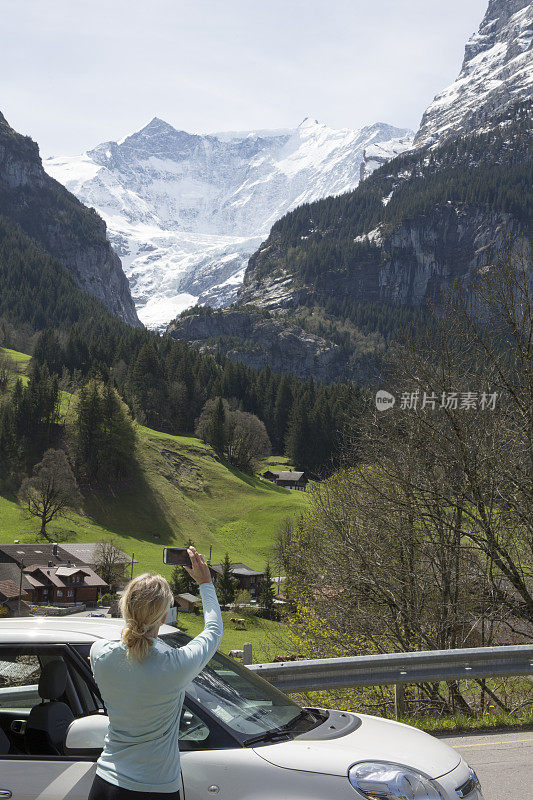 一个女人用智能手机给山、村拍照