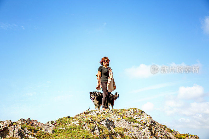 一个成熟的西班牙女人站在遥远的海岸岬角上