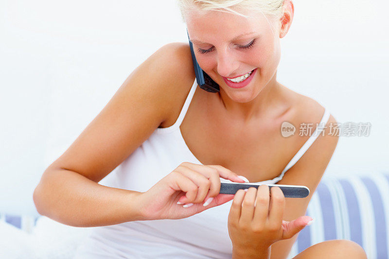 一名年轻女子在用手机交流，正在擦指甲