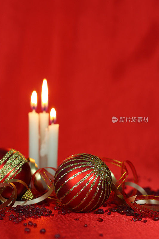红色缎子背景上的圣诞装饰物和白色小蜡烛