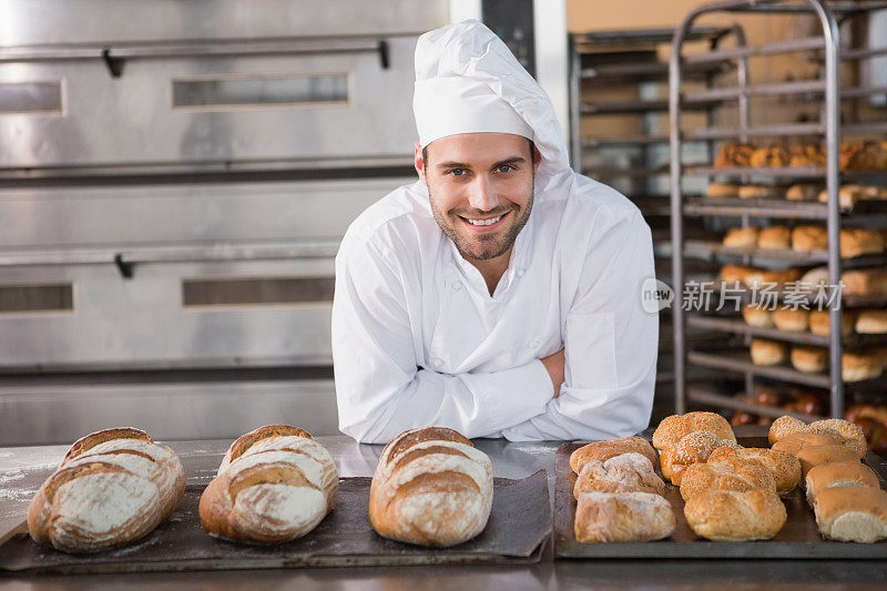 英俊的面包师站在装满面包的托盘旁边
