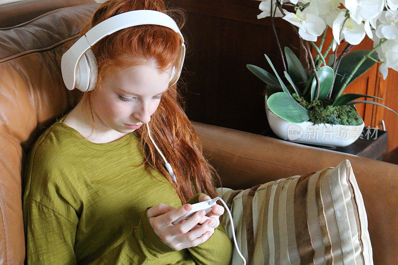 女孩戴着耳机用手机听音乐的画面