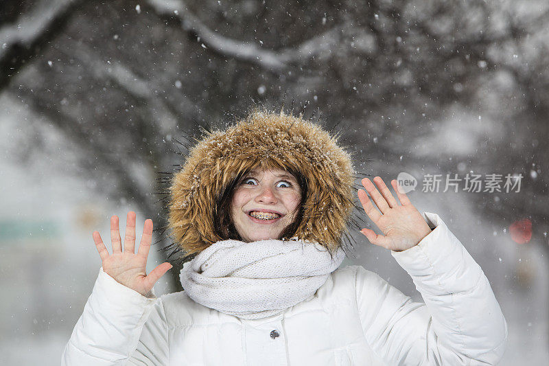 雪下穿着白色夹克的漂亮少女