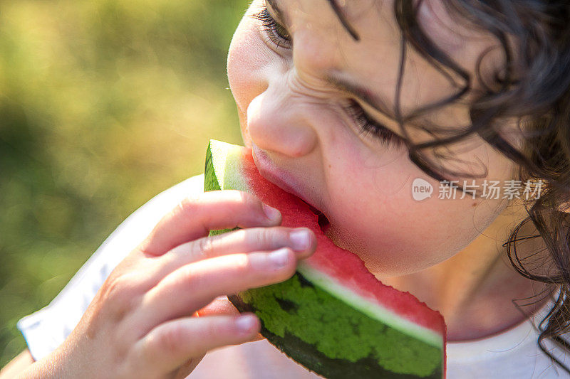 可爱的小女孩咬着多汁的西瓜