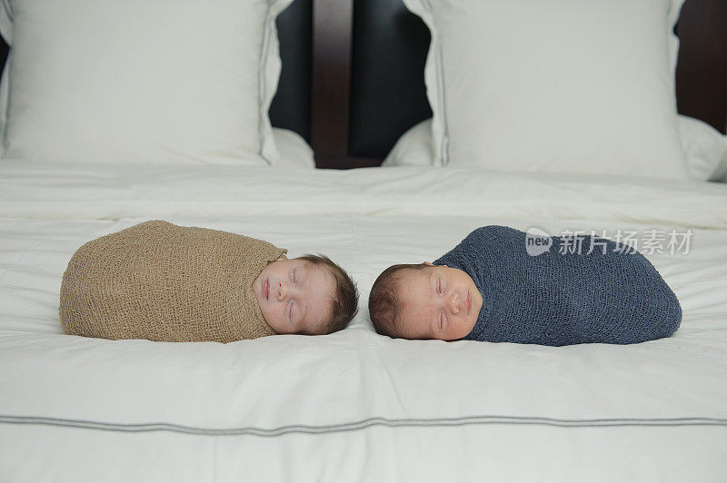 平静的新生双胞胎在床上