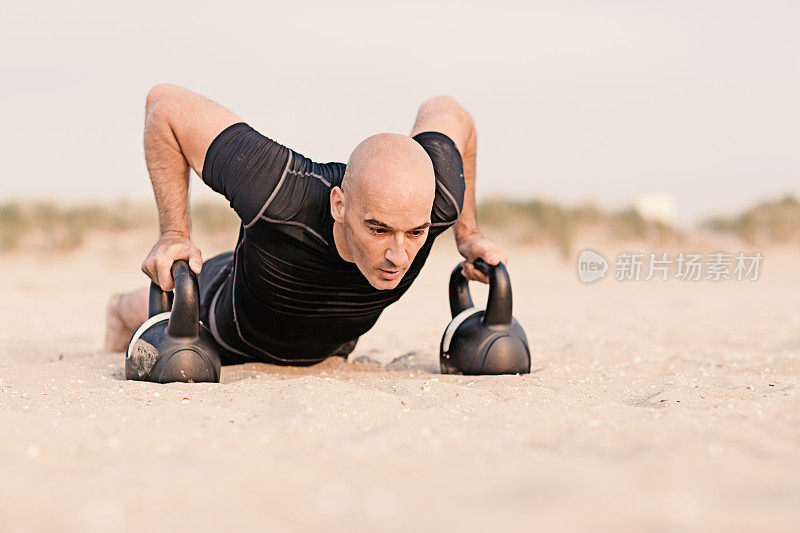 一个戴着哑铃在海滩上锻炼的男人