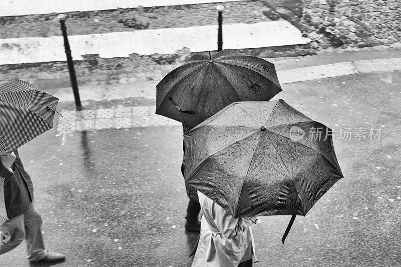 带着雨伞在雨中行走的身份不明的人