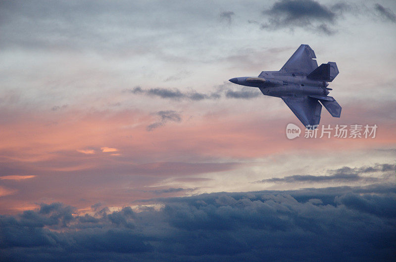 一架F22战斗机在五彩缤纷的天空中穿过云层