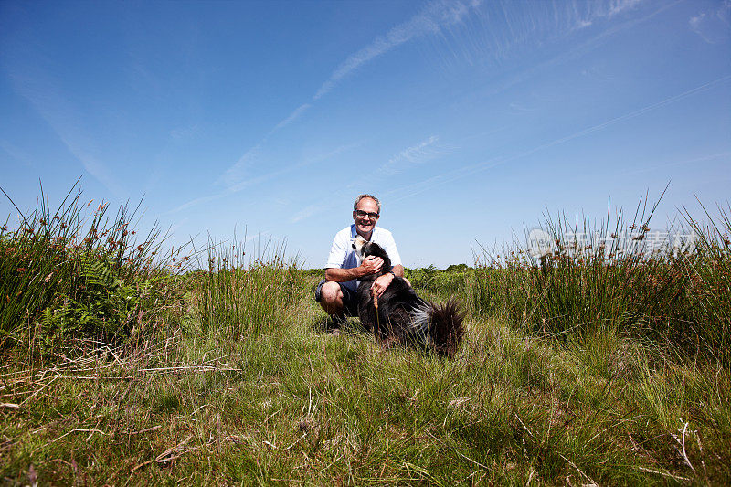 一名成熟男子与边境牧羊犬在威尔士乡村徒步旅行