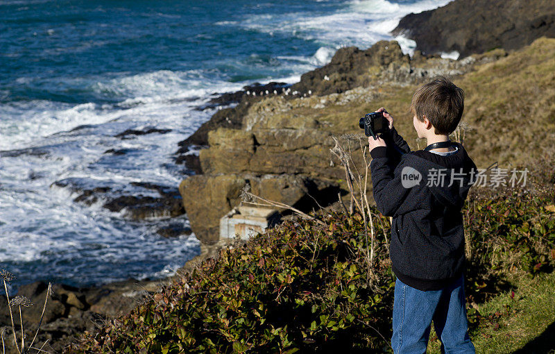 年轻的摄影师正在拍摄海岸，海洋的照片