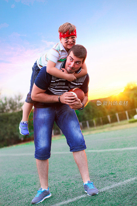 在踢美式足球时，父亲抱着儿子