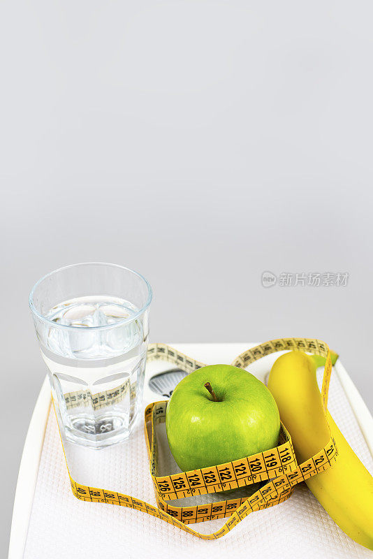 饮食的概念。苹果香蕉杯水卷尺