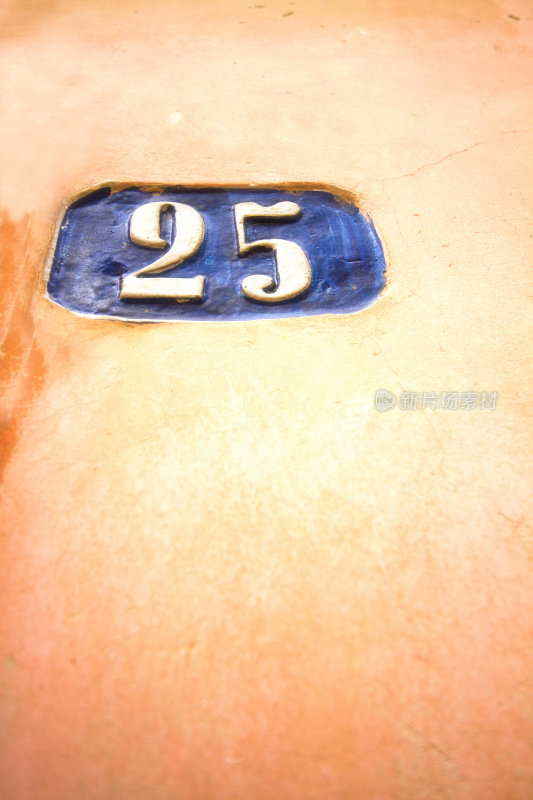 蓝色陶瓷编号25地址瓷砖在漂亮的橙色墙上