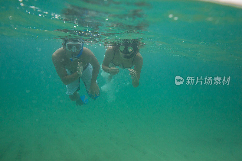 迷人的年轻朋友一起浮潜在热带水域