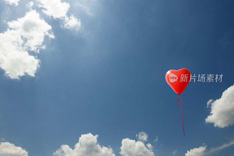 一个红色的心形气球漂浮在蓝天上