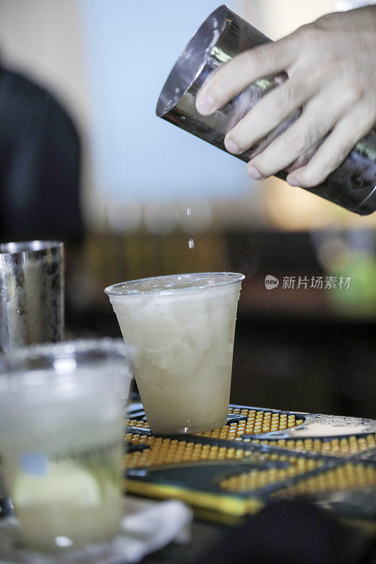 系列:调酒师将酒精饮料从摇瓶倒入塑料杯中