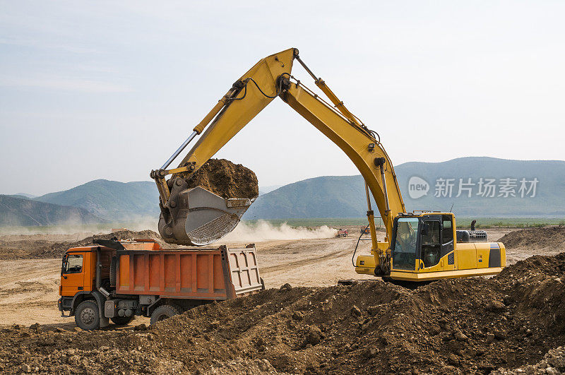 在挖掘机的帮助下，用自卸卡车处理地面