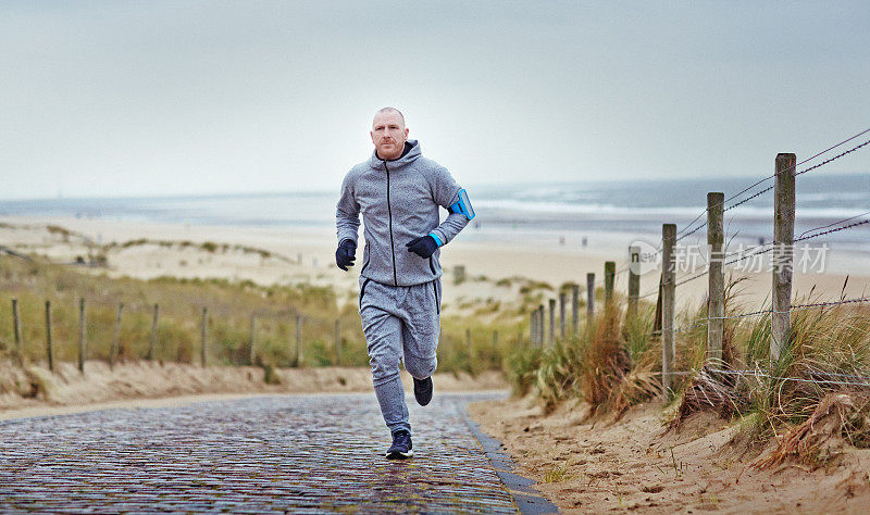一个中年人在冬天的早晨在海边的小路上慢跑